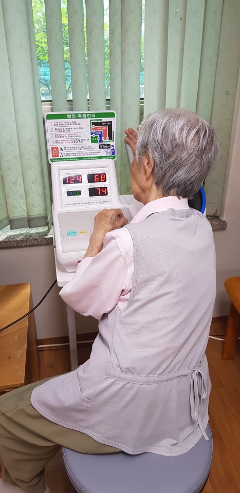 전자혈압계 측정을 하고 있는 어르신.