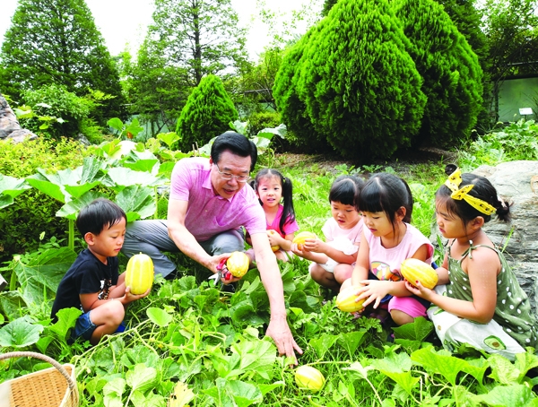 성장현 구청장이 지난 7월 구청광장에서 어린이들과 함께 용산마을농원 향토작물을 수확하고 있다.