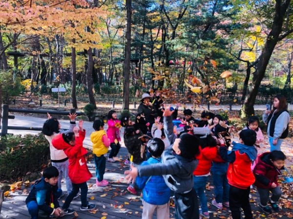 청룡산 유아숲에서 낙엽활용 숲놀이를 하는 어린이들