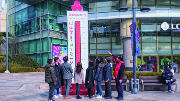 주민들이 목표액을 달성해 100도로 올라간 사랑의온도탑을 보고 있다.